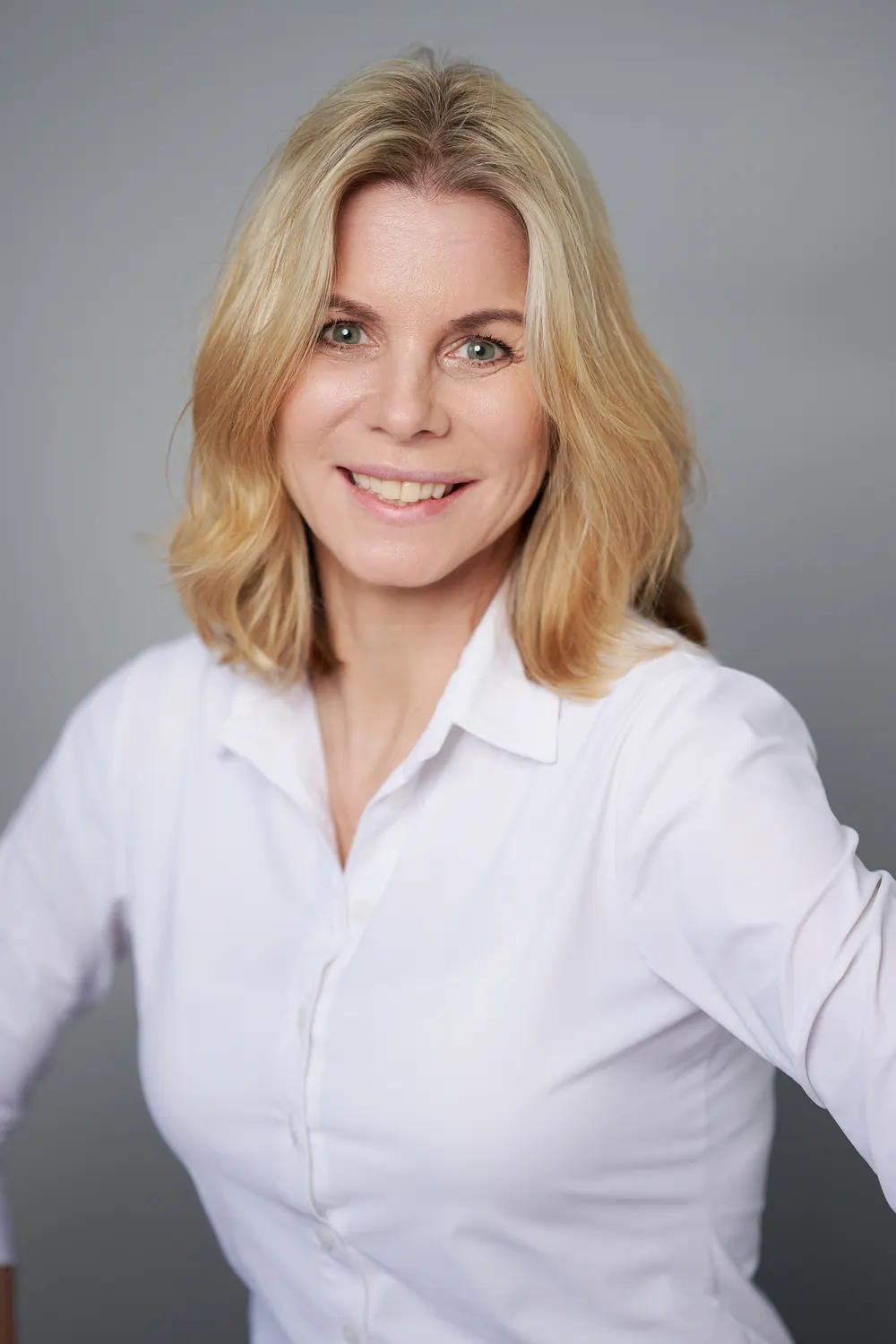 Sympathisches Businessfoto einer Frau mit offenem Lächeln in heller Bluse.