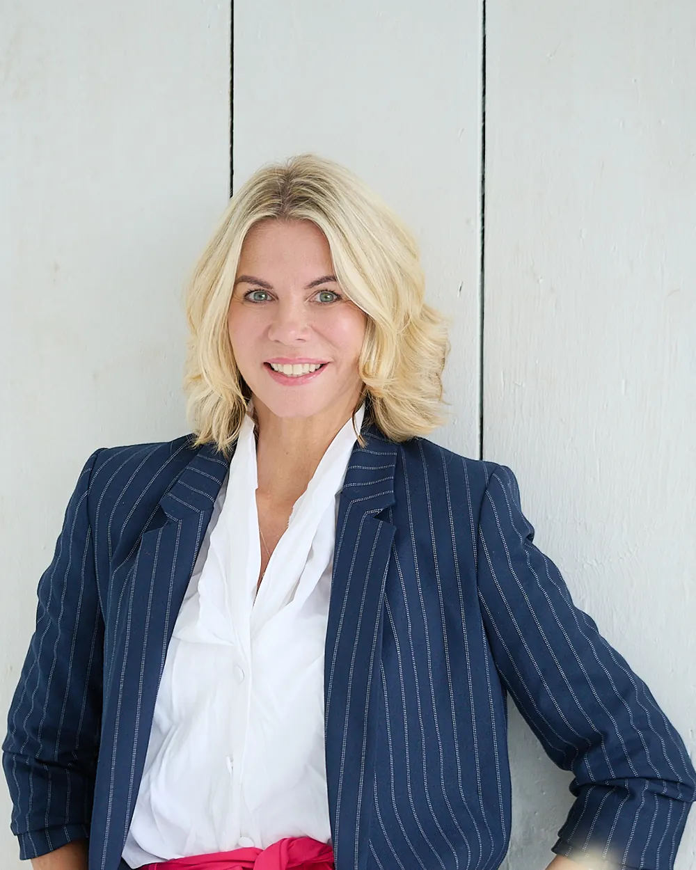 Moderner Corporate Headshot einer Frau im dunkelblauen Nadelstreifen-Blazer vor heller Holzwand.
