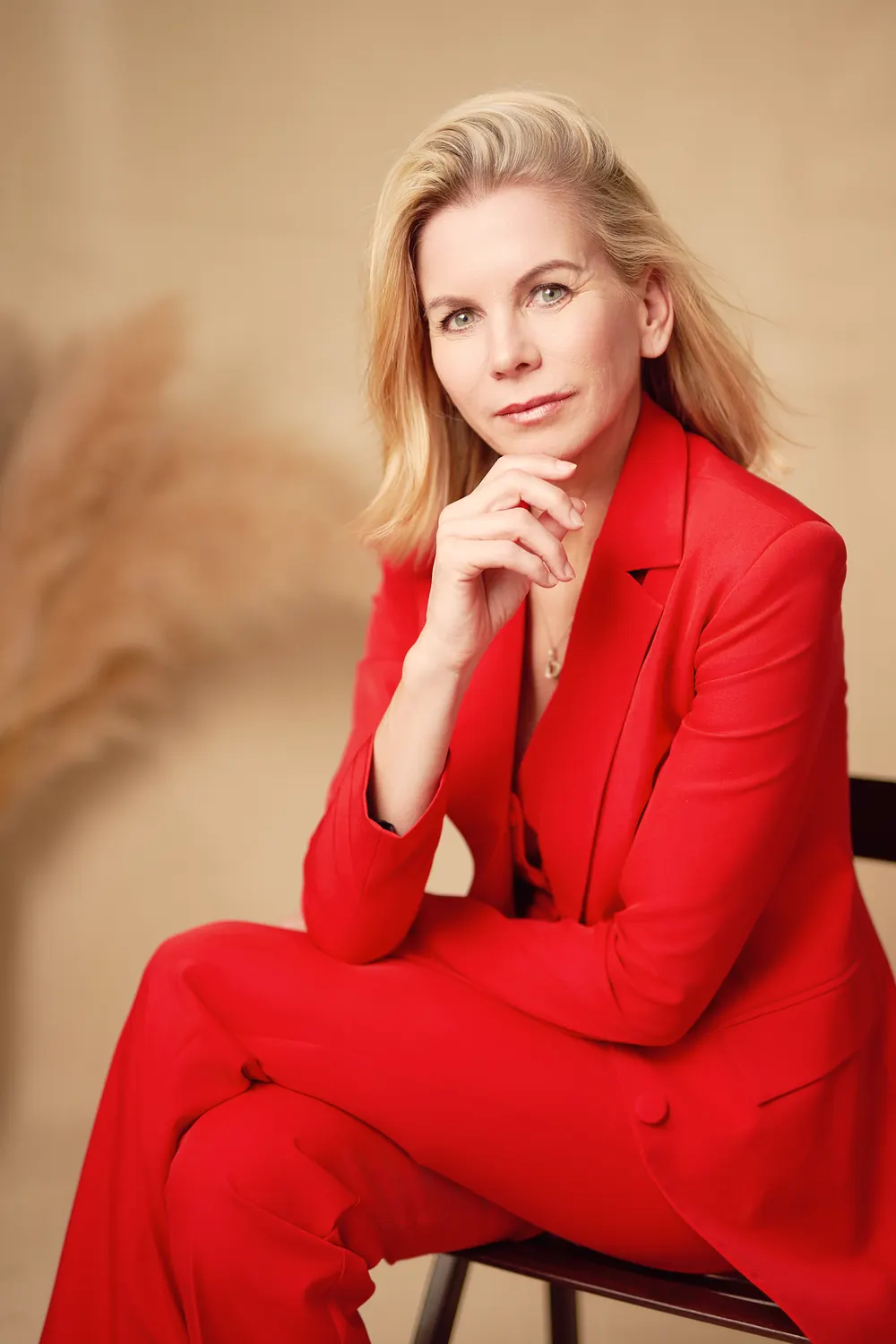 A thoughtful executive in a red blazer, looking calmly into the camera.